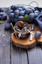 Homemade plum jam in a glass jar and fresh blue plums in a bowl on a dark rustic wooden background with copy space top view. Royalty Free Stock Photo