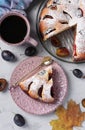 Homemade plum pie, sprinkled icing sugar with cut piece, fresh plums and cup of coffee on gray table, Top view Royalty Free Stock Photo