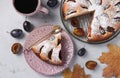 Homemade plum pie, sprinkled icing sugar with cut piece, fresh plums and cup of coffee on light gray table, Top view Royalty Free Stock Photo
