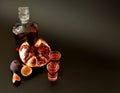 Homemade pomegranate peach liqueur in two hands and a bottle on a black background
