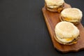 Homemade pork roll egg sandwich on a rustic wooden board on a black surface, side view. Copy space Royalty Free Stock Photo