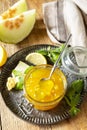 Homemade preserve. Sweet melon and citrus jam or jelly in small glass jar with fresh melon slices on wooden rustic table Royalty Free Stock Photo