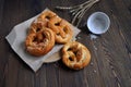 Homemade pretzels, salt and ears of wheat on a dark wooden table