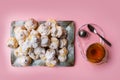 Homemade profiteroles served on a plate with a cup of tea on a pink background. Flat lay.