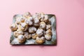 Homemade profiteroles served on a plate in a pink background.