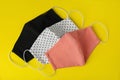 Homemade protective face masks on yellow background, flat lay