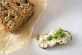 Homemade protein bread on baking paper and sandwich with curd and parsley garnish on a white table, healthy slimming with low carb