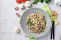 Homemade ptitim pasta with champignons in a plate on light gray table. Horizontal format. Top view