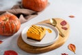 Homemade pumpkin cheesecake pie recipe with cinnamon on white table with pumpkins and autumn leaves on the background. Halloween Royalty Free Stock Photo