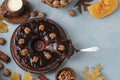 Homemade pumpkin muffin, with a cut out slice, decorated with chocolate icing and walnuts on a light blue background Royalty Free Stock Photo