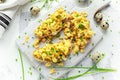 Homemade Quail Scrambled eggs on crispy toast, bread with green onion, chives on white board.