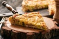 Homemade quiche with leek, ham and cheese on wooden background.