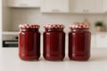 Homemade raspberry jam jars in modern kitchen with red gingham lids Royalty Free Stock Photo