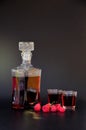 Homemade raspberry liqueur in two glasses and a bottle, ripe berries nearby on a black background Royalty Free Stock Photo