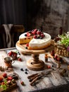 Homemade raspberry sliced biscuit cake with white cream and berries on top on wooden cake stand