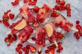 Homemade raspberry, strawberry, apple and currant popsicles on metal plate with ice assorted berries