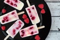 Homemade raspberry vanilla ice pops on a black plate