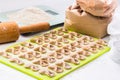 Homemade raw farfalle pasta on cutting board, rolling pin, craftpaper bag of flour and kitchen scale. Pasta of whole grain flour