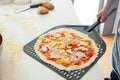 homemade raw pizza with ham pineapple cheese on pizza peel on kitchen counter top with flour spatula and pizza dough Royalty Free Stock Photo