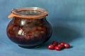 Homemade red cornel jam in a glass jar and red cornel berrie