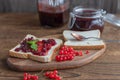 Homemade red currant jam in a glass jar and a number of berries on a wooden background. Toast or bread with marmalade for Royalty Free Stock Photo