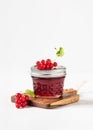 Homemade red currant jam or jelly in a glass jar with fresh berries on a light background. Royalty Free Stock Photo