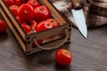 Homemade red tomatoes in a wooden box on a dark wooden background, textiles, knife, cutting Board and sliced tomato Royalty Free Stock Photo