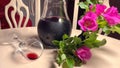 Homemade red wine in glass jug, flowers and wine glass on white table Royalty Free Stock Photo