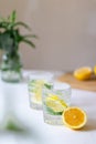 Homemade refreshing summer lemonade drink with lemon slices and ice in glasses with flowers bouquet in a vase on the Royalty Free Stock Photo