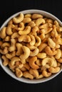Homemade Roasted and Salted Cashews in a Bowl on a black surface, top view. Flat lay Royalty Free Stock Photo