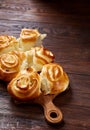 Homemade rose buns on wooden cutting board over rustic vintage background, close-up, shallow depth of field Royalty Free Stock Photo