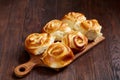 Homemade rose buns on wooden cutting board over rustic vintage background, close-up, shallow depth of field Royalty Free Stock Photo