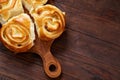 Homemade rose buns on wooden cutting board over rustic vintage background, close-up, shallow depth of field Royalty Free Stock Photo