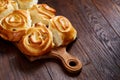 Homemade rose buns on wooden cutting board over rustic vintage background, close-up, shallow depth of field Royalty Free Stock Photo