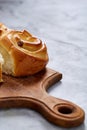 Homemade rose buns on wooden cutting board over white textured background, close-up, shallow depth of field Royalty Free Stock Photo