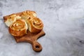 Homemade rose buns on wooden cutting board over white textured background, close-up, shallow depth of field Royalty Free Stock Photo