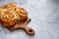 Homemade rose buns on wooden cutting board over white textured background, close-up, shallow depth of field Royalty Free Stock Photo