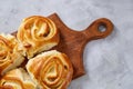 Homemade rose buns on wooden cutting board over white textured background, close-up, shallow depth of field Royalty Free Stock Photo