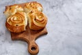 Homemade rose buns on wooden cutting board over white textured background, close-up, shallow depth of field Royalty Free Stock Photo