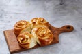 Homemade rose buns on wooden cutting board over white textured background, close-up, shallow depth of field Royalty Free Stock Photo