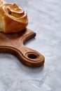 Homemade rose buns on wooden cutting board over white textured background, close-up, shallow depth of field Royalty Free Stock Photo