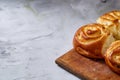 Homemade rose buns on wooden cutting board over white textured background, close-up, shallow depth of field Royalty Free Stock Photo