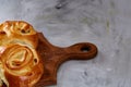 Homemade rose buns on wooden cutting board over white textured background, close-up, shallow depth of field Royalty Free Stock Photo