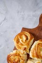 Homemade rose buns on wooden cutting board over white textured background, close-up, shallow depth of field Royalty Free Stock Photo