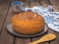 Homemade round bread with flax and sesame seeds on a round plate on an old plank table, frying and a cotton towel with a pattern Royalty Free Stock Photo