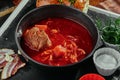 Red borsch made of beetrot, vegetables and meat with sour cream in a black plate on a copper background Royalty Free Stock Photo