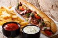 Homemade sandwich with bacon and vegetables served with french fries and sauces close-up. horizontal Royalty Free Stock Photo