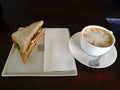 Homemade sandwich with cheese and ham and Latte coffee cup in n a in white plate on green wooden table Royalty Free Stock Photo