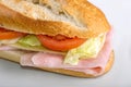 Homemade sandwich with ham, salad, chesse and tomatoes in white bread baguette