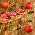 Homemade sandwich with smoked sausage, salami and tomatoes on old wooden table. Thinly spicy slice. Typical italian or spanish sn Royalty Free Stock Photo